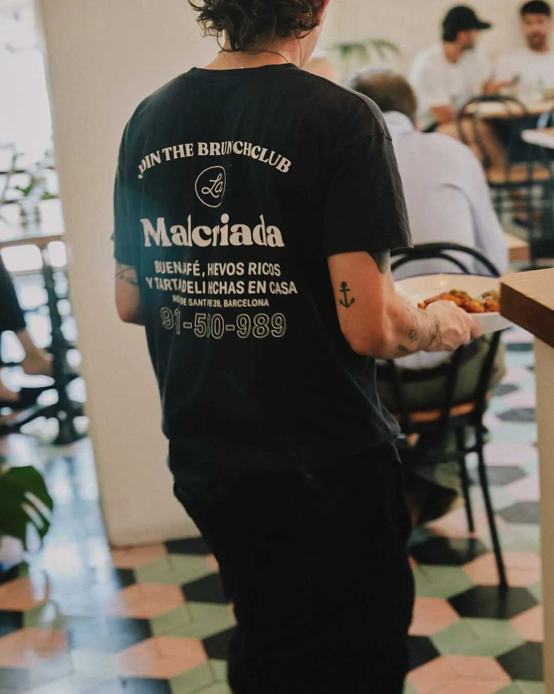 Una cambrera serveix a la sala, amb la samarreta «Join the brunch club»