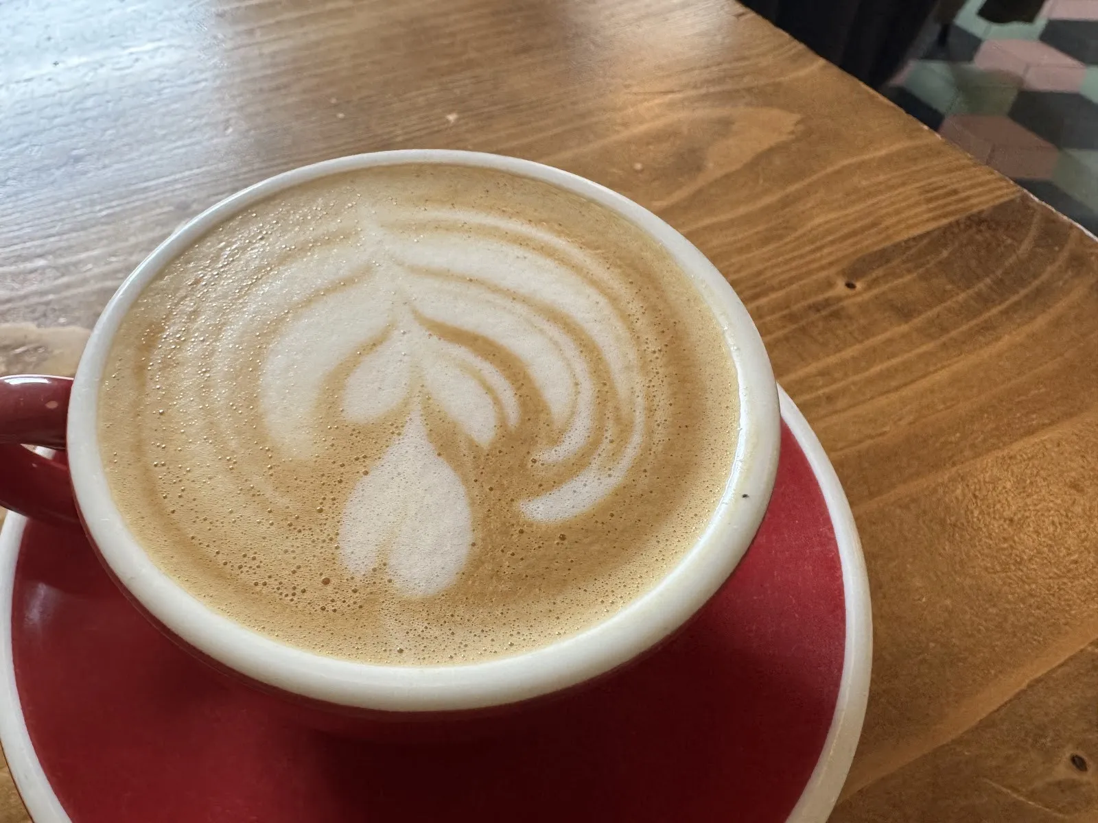 Un cafè amb llet amb un dibuix a l’escuma en una tassa vermella