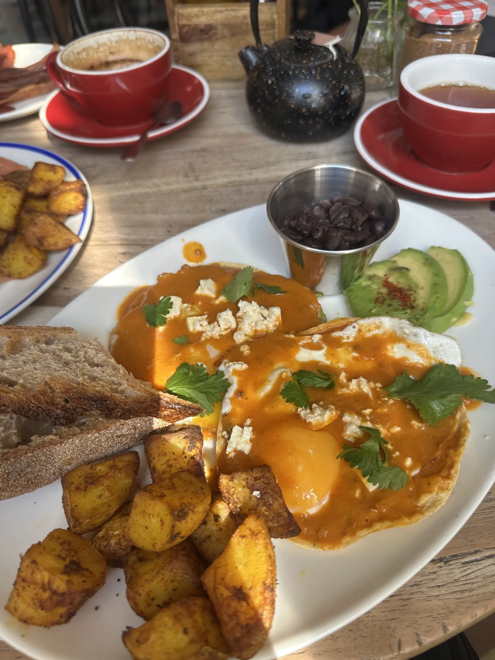 Ous amb salsa, formatge, alvocat, patates i pa torrat, amb tes i cafès
